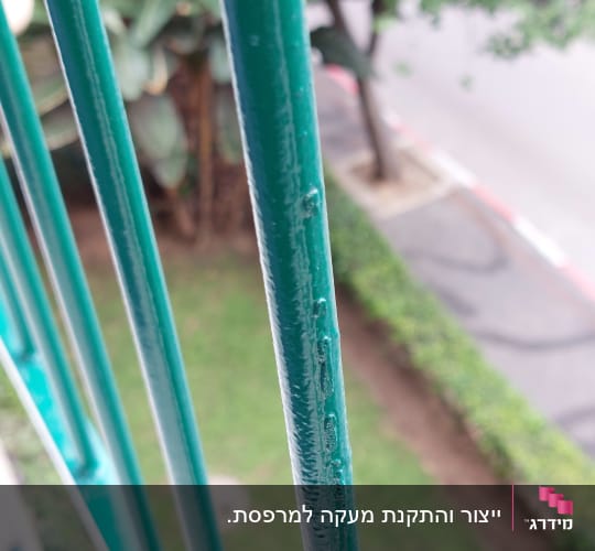 תקריב של מוטות מתכת ירוקים בסורג או מעקה מרפסת